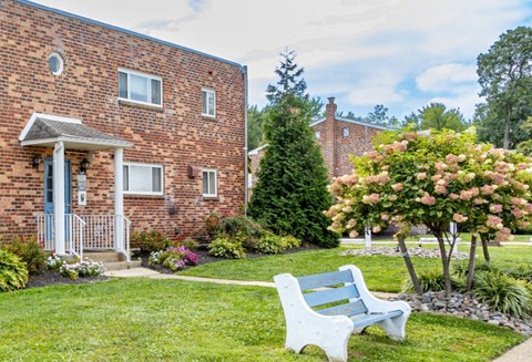 A white bench sits in front of a brick building.