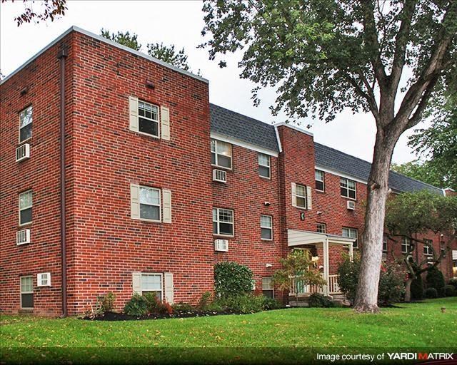 a red brick building with a tree in the yard