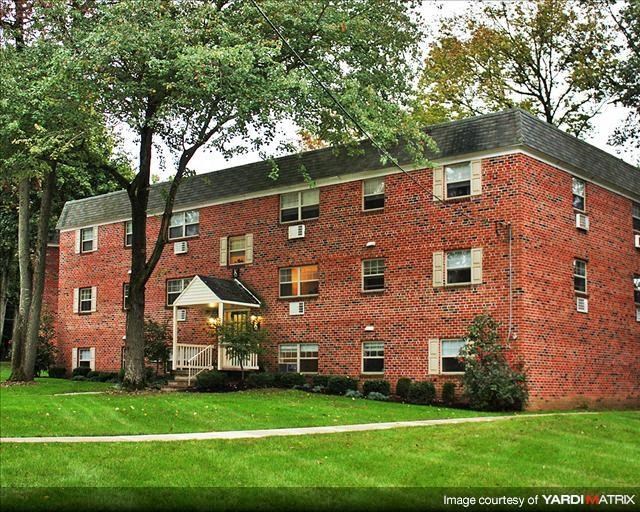 a red brick building with a green lawn and trees