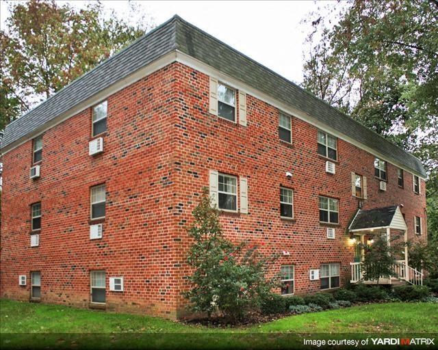 a red brick building with a green lawn and trees