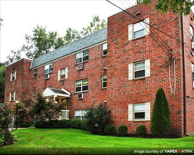 a red brick apartment building with a green yard