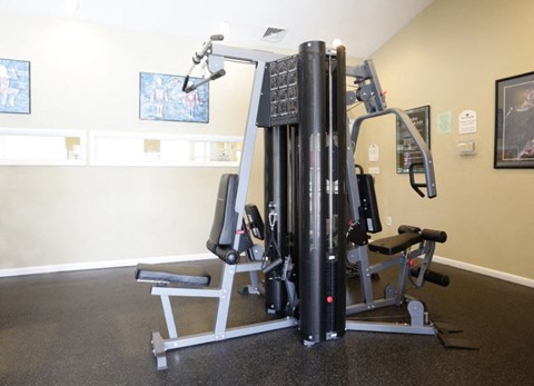 A gym with a weight machine and a bench.