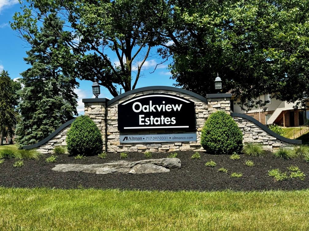 A sign for Oakview Estates is displayed in front of a building.