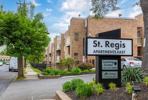 A sign for St. Regis Apartments East is in front of a brick building.