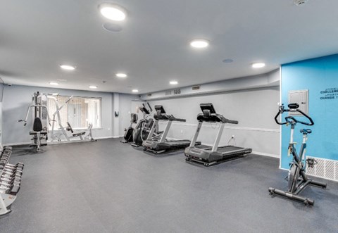 A gym with a variety of equipment including treadmills, weights, and exercise bikes.