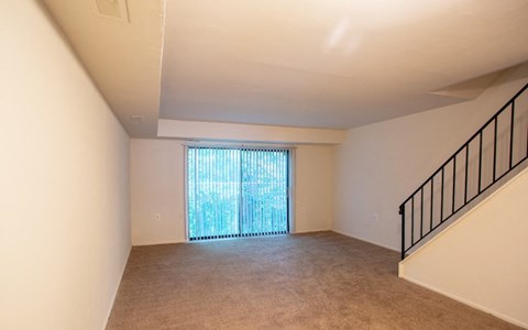 A room with a carpeted floor and a staircase with a railing.