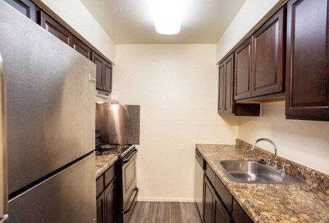 A kitchen with a granite counter top and stainless steel appliances.