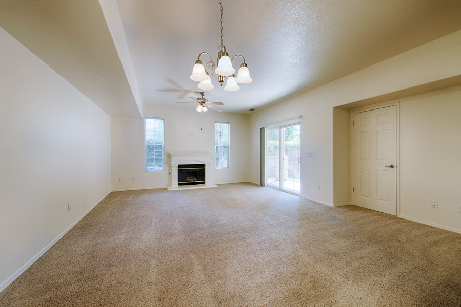 an empty living room with a fireplace and a ceiling fan