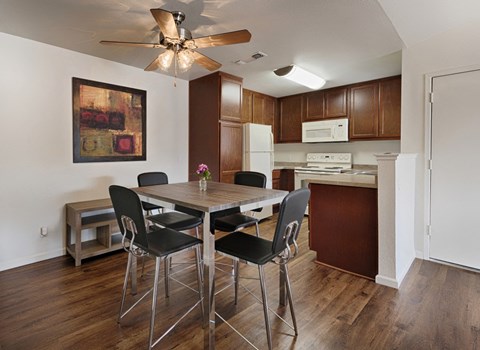 a dining room table with four chairs in front of a kitchen