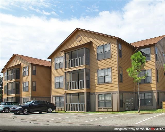 an apartment building with cars parked in a parking lot