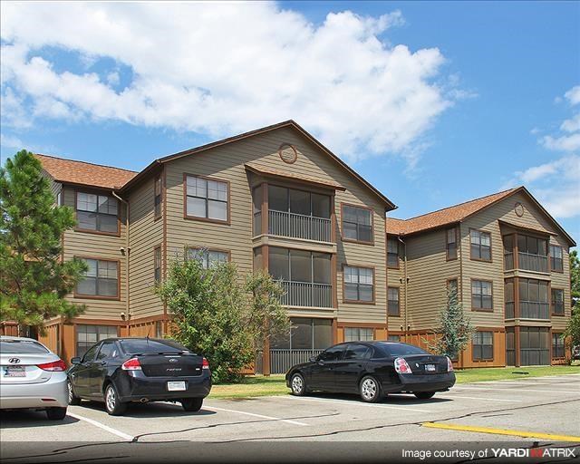 a large apartment building with cars parked in a parking lot