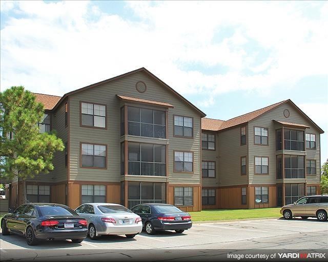 a large apartment building with cars parked in a parking lot