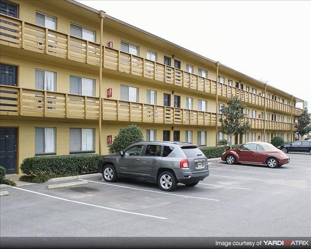 an apartment building with cars parked in a parking lot