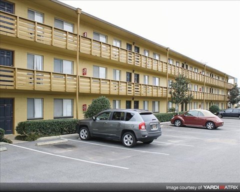 an apartment building with cars parked in a parking lot