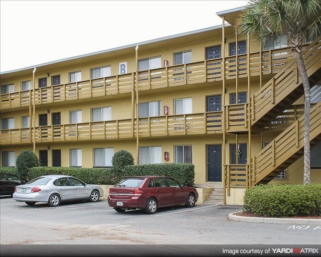 a yellow apartment building with cars parked in front of it