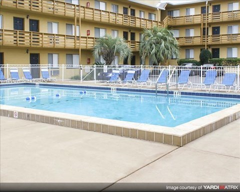 a swimming pool with blue chairs in front of a hotel