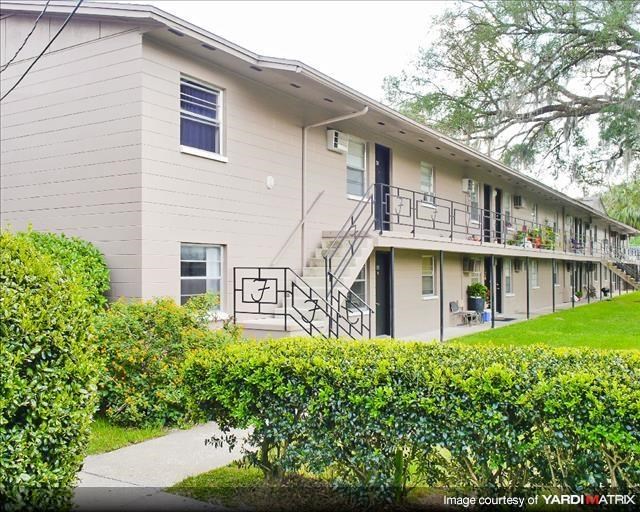 a white building with a balcony and a yard