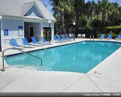 a swimming pool with blue chairs and a white building