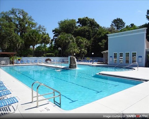 a large swimming pool with a building and chairs