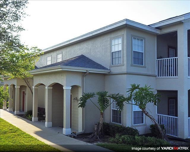 a white house with palm trees and a sidewalk