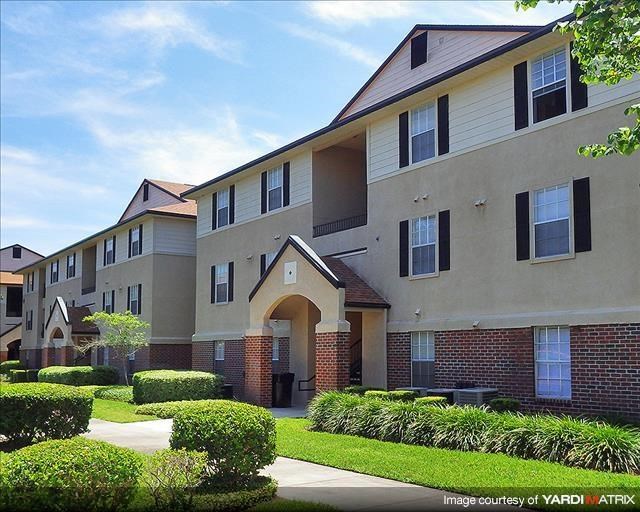 an apartment building with a sidewalk and grass