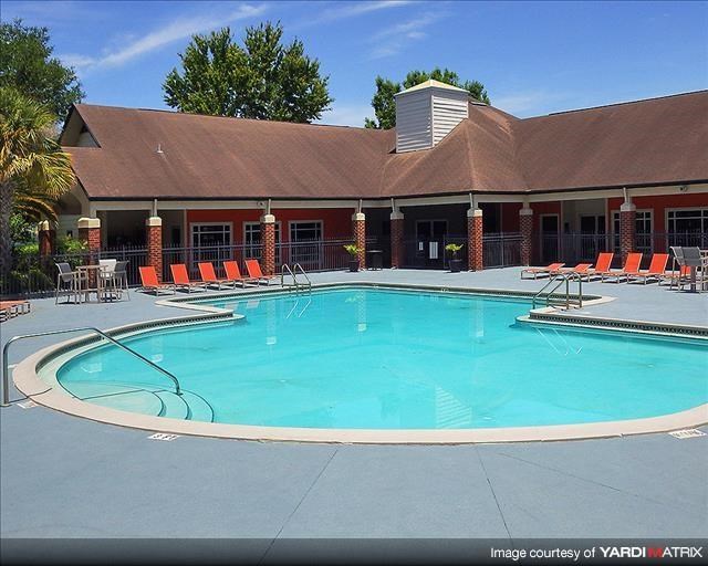 a swimming pool with orange chairs in front of a building