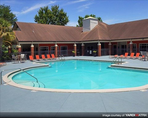 a swimming pool with orange chairs in front of a building