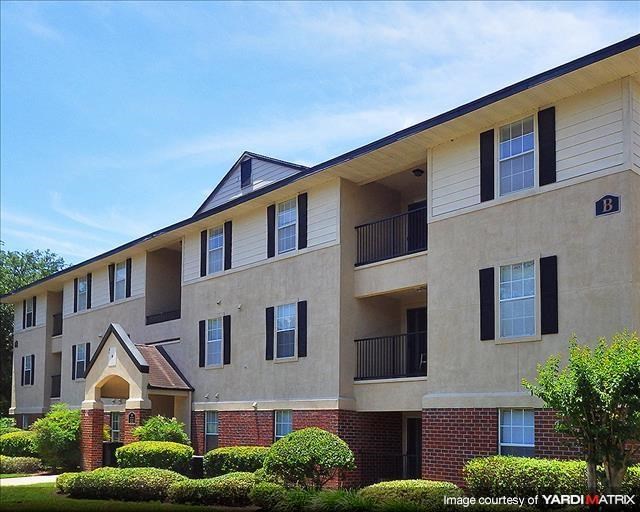 a large apartment building with a yard and bushes