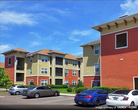 a row of apartment buildings with cars parked in a parking lot