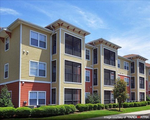 a row of apartment buildings with grass and trees