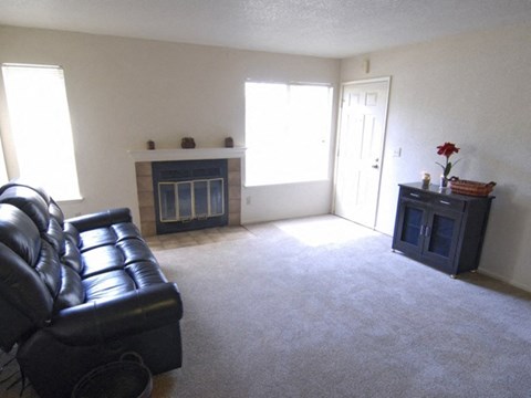 a living room with a black leather couch and a fireplace