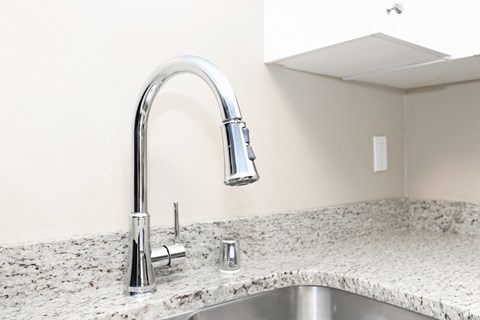 a kitchen sink with a chrome faucet and a marble counter top