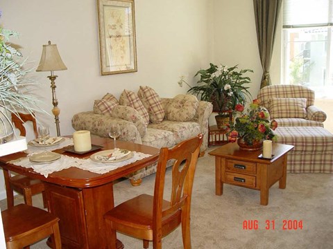 A living room with a couch, chair, and table set for a meal.