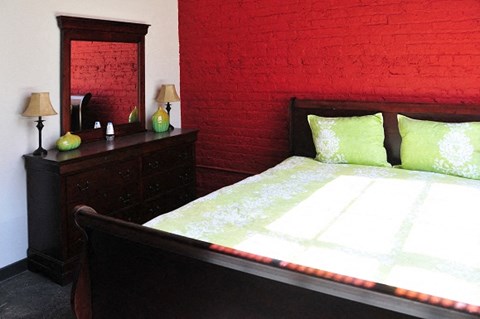 a bedroom with a bed and a red brick wall