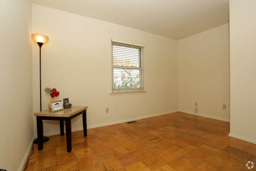 a room with a wooden floor and a window and a table