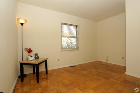 a room with a wooden floor and a window and a table