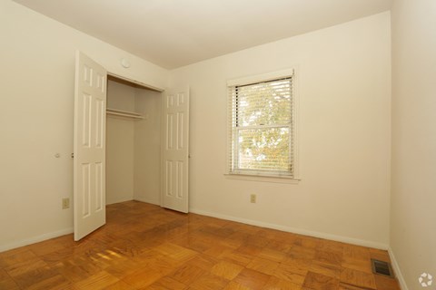 a bedroom with wood floors and a window and a closet