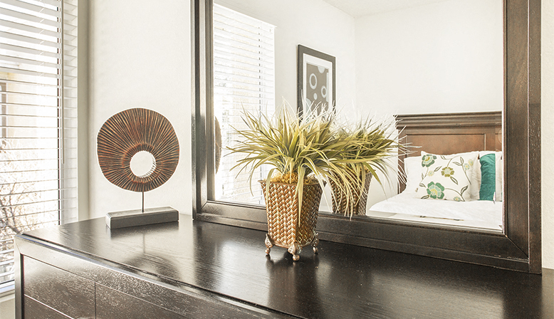 a bedroom with a large mirror and a table with a plant on it