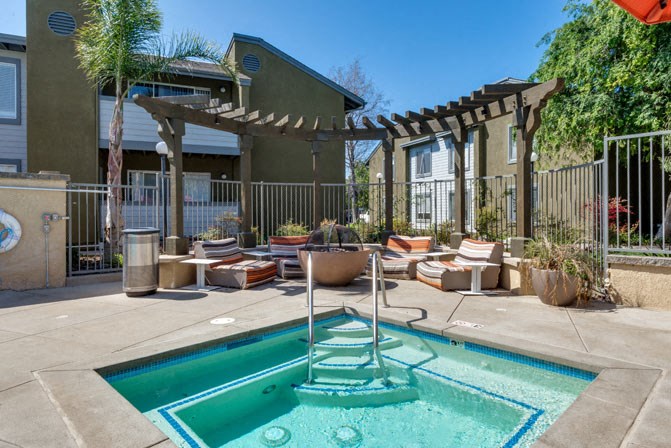a pool with lounge chairs and a pergola next to a house