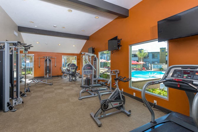 a gym with cardio equipment and a view of a swimming pool