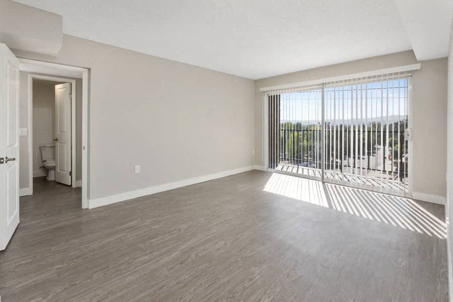 an empty living room with a large window and wood flooring