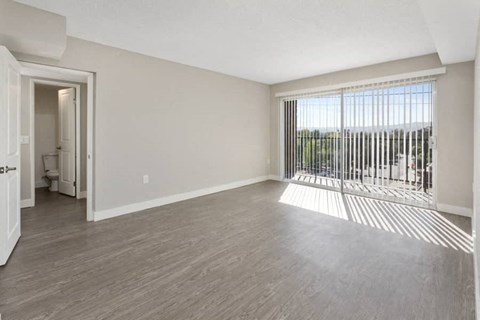 an empty living room with a large window and wood flooring