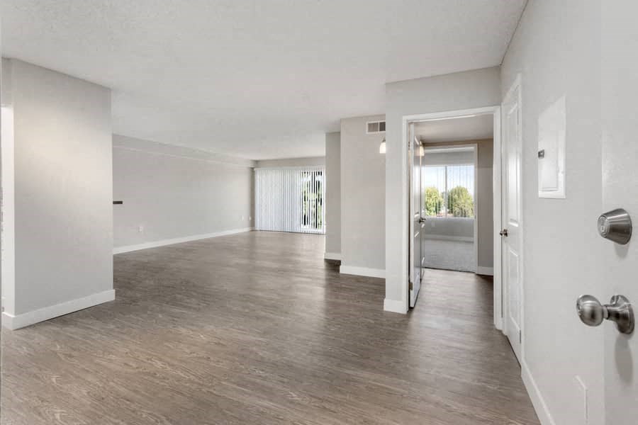 an empty living room and hallway with white walls and wood floors