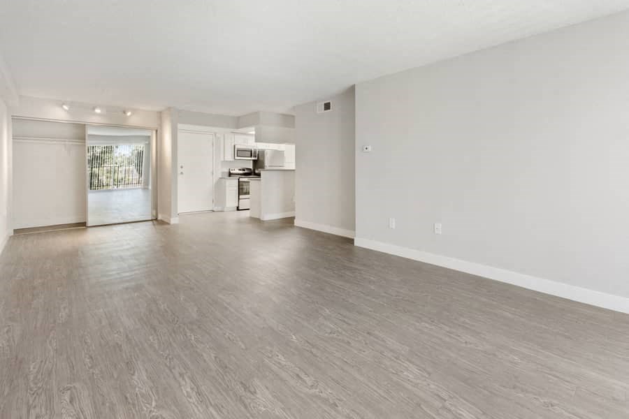 an empty living room and kitchen with wood flooring