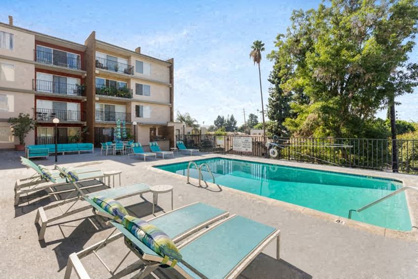a swimming pool with chaise lounge chairs and a hotel in the background