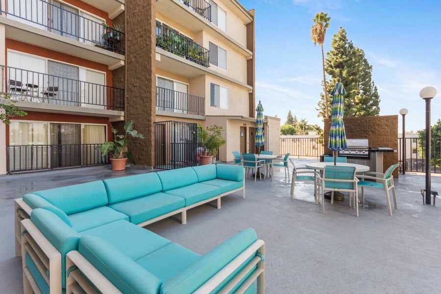 an apartment patio with blue couches and tables and a piano