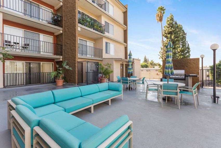 a patio with turquoise couches and chairs and a grill