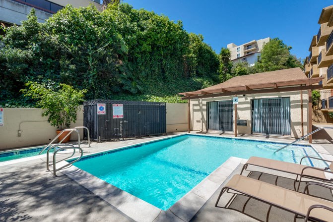 a swimming pool with two chairs and a building in the background