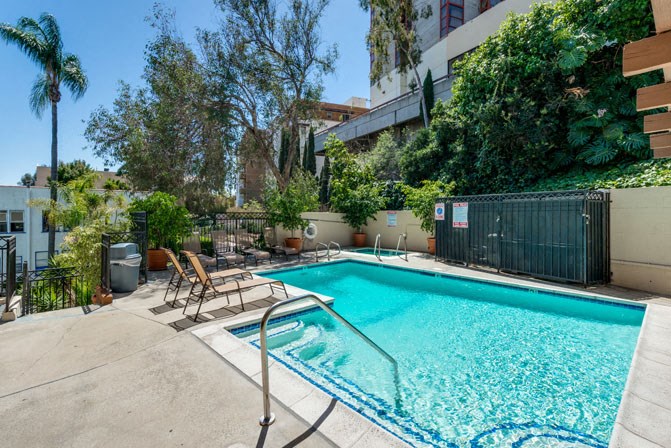 a swimming pool with chairs and a fence around it