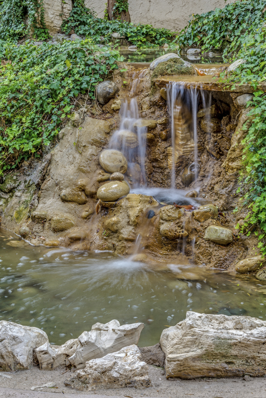 a small waterfall in a garden with a pond